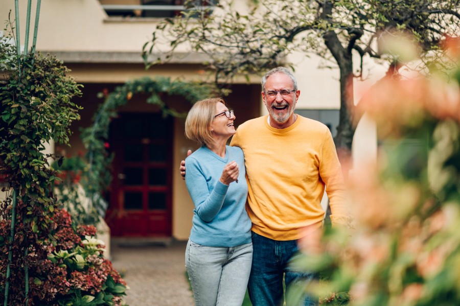 Senior couple embracing outside their home