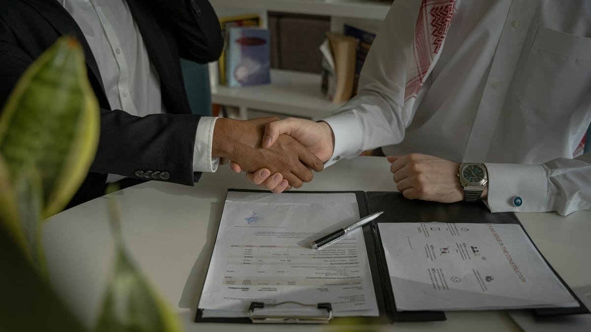 Business partners shaking hands over a signed agreement